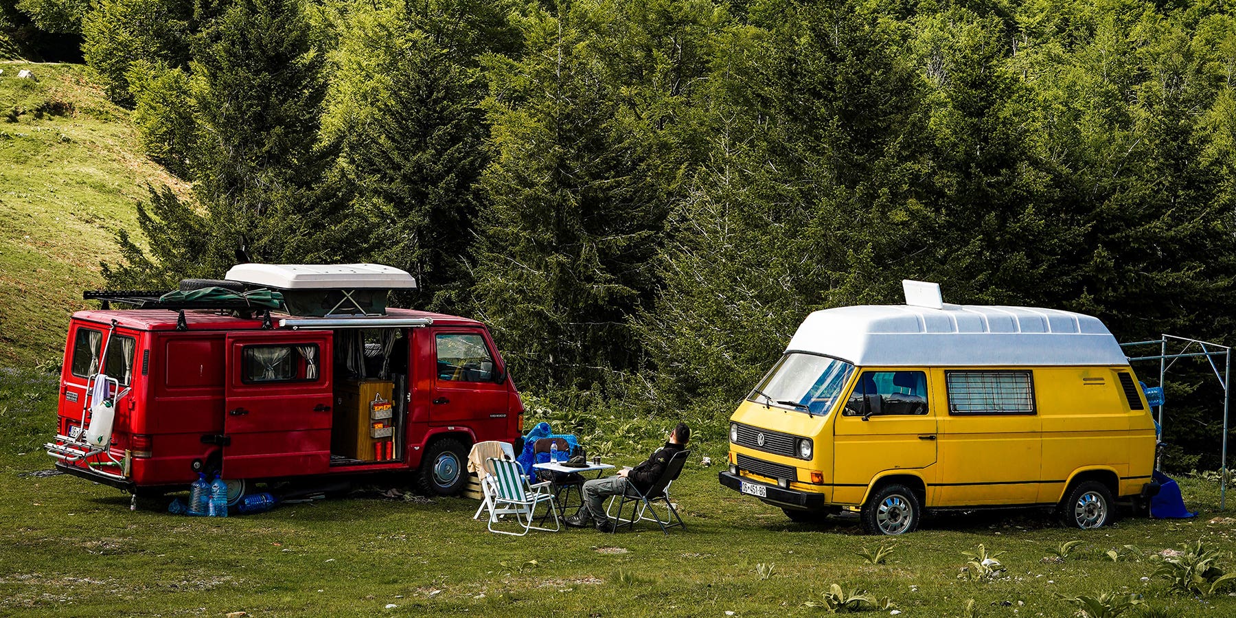 A large red converted campervan, and a medium yellow VW T3 campervan